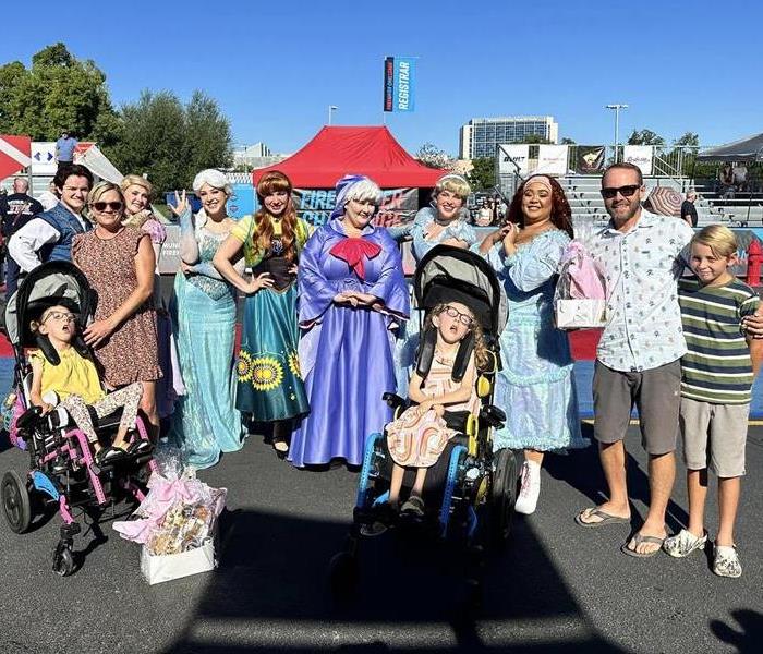 Two girls with Terimanl Illness, standing alongside their family members and disney princesses after their wish granted